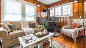 A cozy living room with a stone fireplace, wooden walls, and a comfortable seating area.