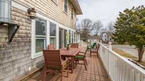 A wooden deck with a table and chairs, a potted plant, and a white picket fence. - Laurel Beach-Milford (Milford)