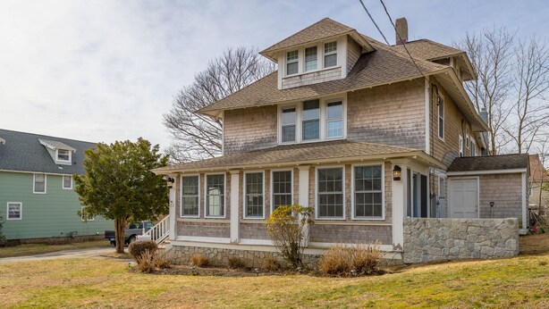 A two-story house with a stone foundation, large windows, and a small porch. - Laurel Beach-Milford (Milford)