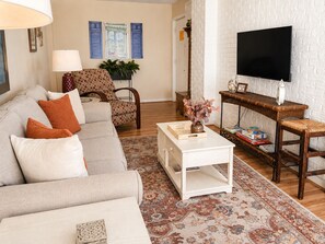 A living room with a sofa, armchair, coffee table, and a television.