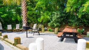 An outdoor seating area with a wooden table and chairs, surrounded by gravel and wooden posts. - Easy Breezy 2 Bd, 1st Floor, 4 Min to Beach (Isle of Palms)