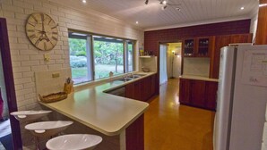 Una cocina con un reloj grande, una ventana y un refrigerador.