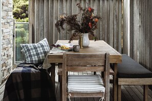 Enjoy a meal al fresco at this outdoor dining area, featuring a wooden table and comfortable seating.