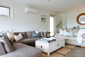 Ein Wohnzimmer mit einer Eckcouch, einem Couchtisch und einem runden Spiegel an der Wand.