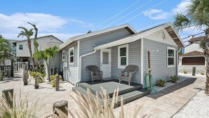 A single-story house with a porch, two wicker chairs, and a hose for outdoor use.