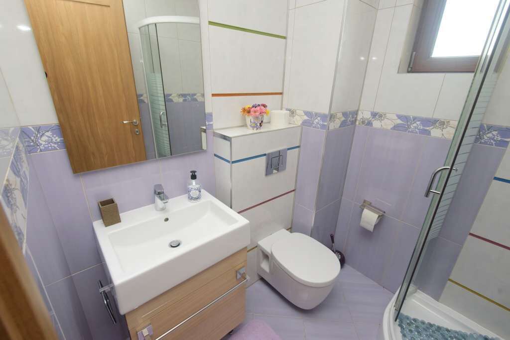 Ein Badezimmer mit weißem Waschbecken, Spiegel, Toilette und Dusche.