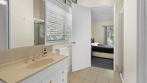 A bathroom with a sink, mirror, and window with blinds.