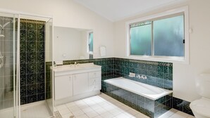 A modern bathroom with a walk-in shower, a double sink vanity, a bathtub, and a toilet.