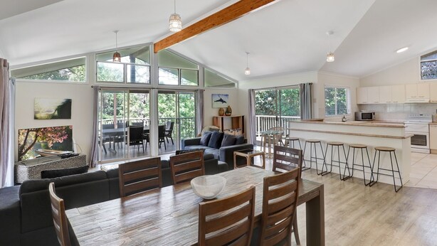 A spacious living area with a large dining table, multiple chairs, and a kitchen area with a bar.