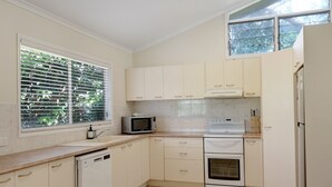 A compact kitchen with white cabinets, a microwave, a stove, and a dishwasher.