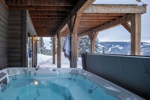 Un bain à remous doté d’une structure en bois et offrant une vue sur des montagnes enneigées.