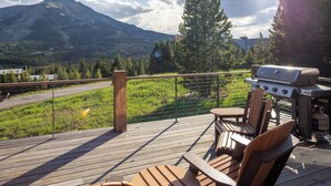 Eine Terrasse mit Grill, Stühlen und Blick auf einen Berg.