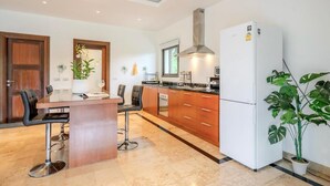 A modern kitchen with a central island, wooden cabinets, a white refrigerator, and a potted plant. - 2 Bedroom Pool Villa Nature SDV004 By Samui Dream Villas (Mae Nam)