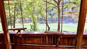 A wooden deck with two benches overlooking a scenic view of a lake and trees.