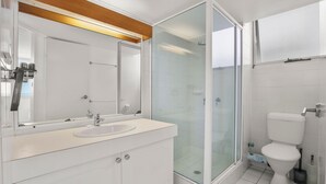 Ein modernes Badezimmer mit Duschkabine aus Glas, einem weißen Waschbecken und einer Toilette.