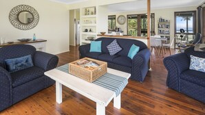 A living room with a sofa set, a coffee table, and a dining area with a table and chairs. - Pet friendly property with water views (Point Lookout)