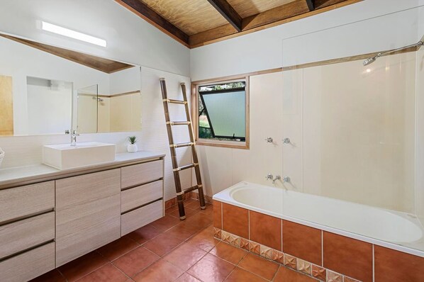 Un baño con una bañera grande, un tocador con espejo y una ventana.