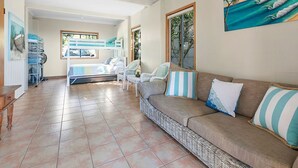Un amplio espacio de sala con sofá, sillones y vistas al exterior.