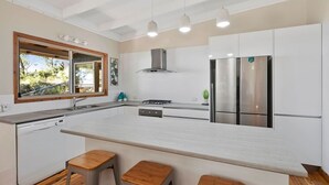 Una cocina moderna con armarios blancos, electrodomésticos de acero inoxidable y una isla grande con taburetes.
