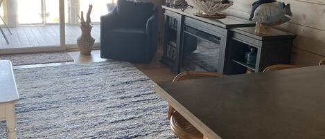 A living room with a large window, a blue armchair, a wooden coffee table, a lamp, and a fish sculpture.