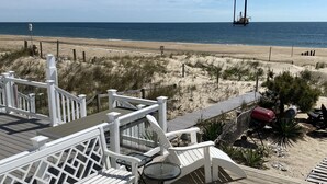 A wooden deck with white railings, a barbecue grill, and a view of the beach and ocean. - Oceanfront Townhome With Breathtaking Views From 3 Deck Levels (Bethany Beach)