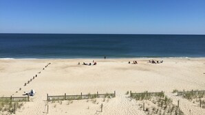 A wide sandy beach with a wooden fence and a clear blue sky. - Oceanfront Townhome With Breathtaking Views From 3 Deck Levels (Bethany Beach)