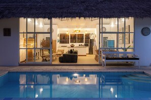 A modern home with a pool, featuring a dining area, kitchen, and living room with a thatched roof. - Thatched Tropical Garden Home with Pool in Trendy Seminyak (Seminyak)