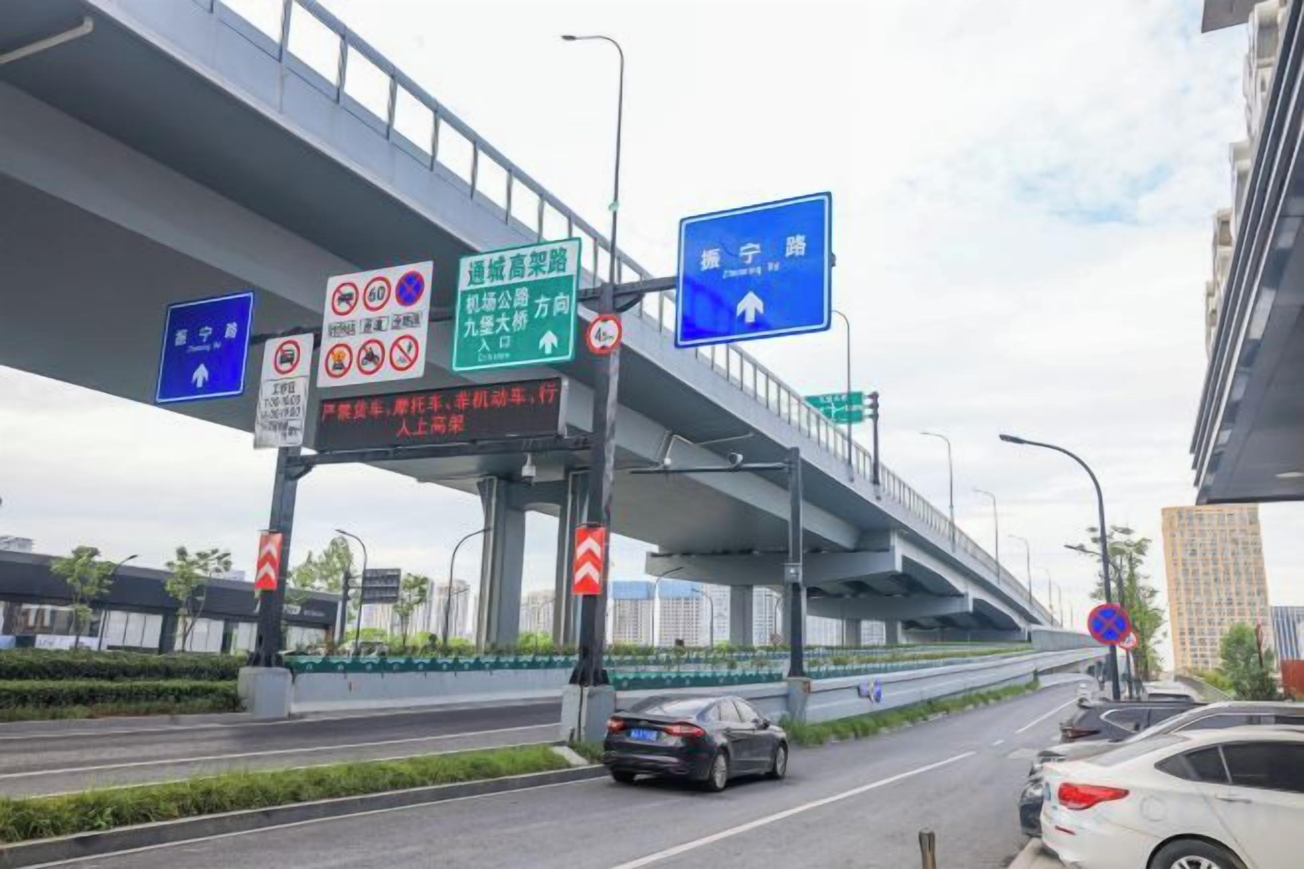 Un nudo vialatorio de múltiples niveles con señales de dirección, un paso peatonal y un automóvil en la carretera.