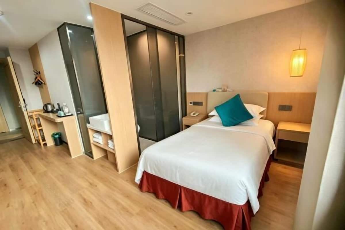 A hotel room with a bed, bedside table, nightstand, and a wardrobe.