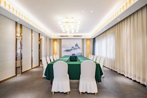 A conference room with a long table, chairs, and a painting on the wall. - yiduo hotel (Hangzhou)