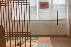 A room with a wooden partition, a glass door, and a colorful play mat on the floor. - yiduo hotel (Hangzhou)