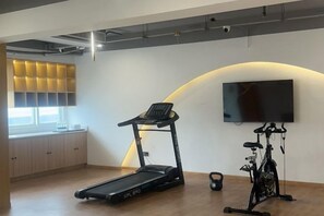 A gym with a treadmill, stationary bike, and weights. - yiduo hotel (Hangzhou)