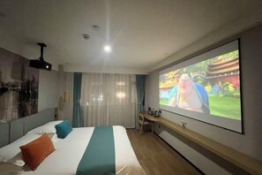 Una habitación de hotel con una cama, una pantalla de televisión, un escritorio y un proyector.
