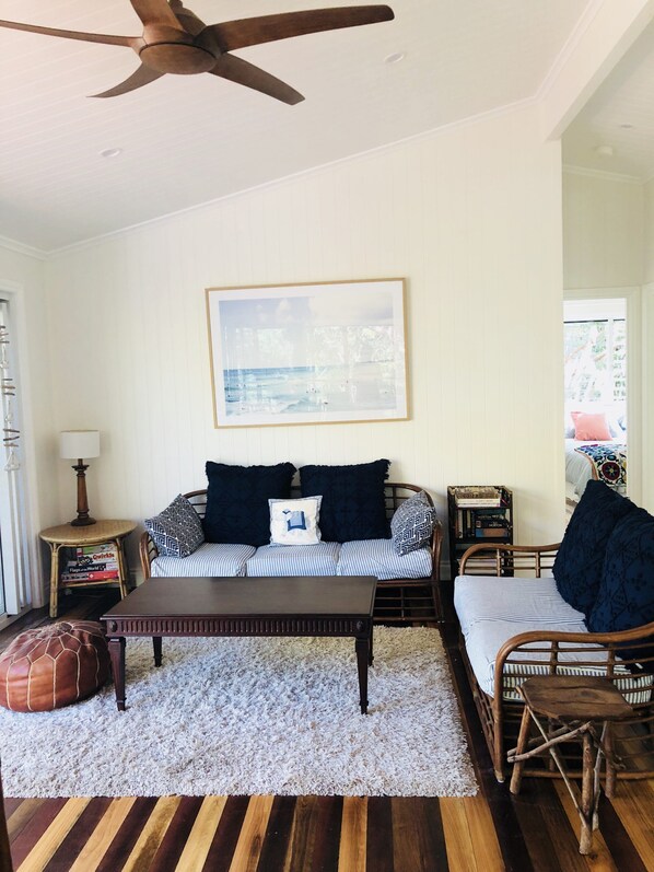 A living room with a wooden ceiling fan, a framed picture on the wall, a sofa with striped cushions, a coffee table, and a wicker chair. - Walking distance to all popular amenities of Point Lookout (Point Lookout)