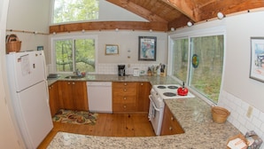 A kitchen with wooden cabinets, a granite countertop, a stove, and a refrigerator. - Spacious and modern home, close to beach, Tom's Hill private setting. Home AC (Truro)