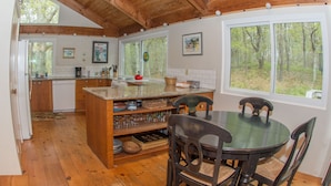 A rustic kitchen with wooden beams, a dining table, and chairs. - Spacious and modern home, close to beach, Tom's Hill private setting. Home AC (Truro)