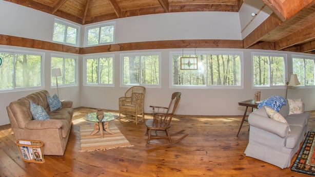 A spacious room with wooden floors, a high ceiling, and large windows offering a view of the forest. - Spacious and modern home, close to beach, Tom's Hill private setting. Home AC (Truro)