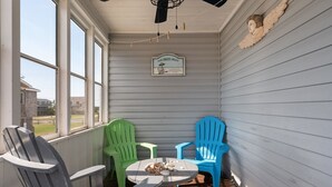 En inglasad veranda med två Adirondack-stolar, ett litet bord och en takfläkt.