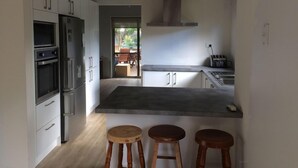 Eine moderne Küche mit Edelstahlgeräten, einer großen Kochinsel und Holzstühlen.