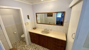 Une salle de bain avec un lavabo, un miroir et des toilettes.