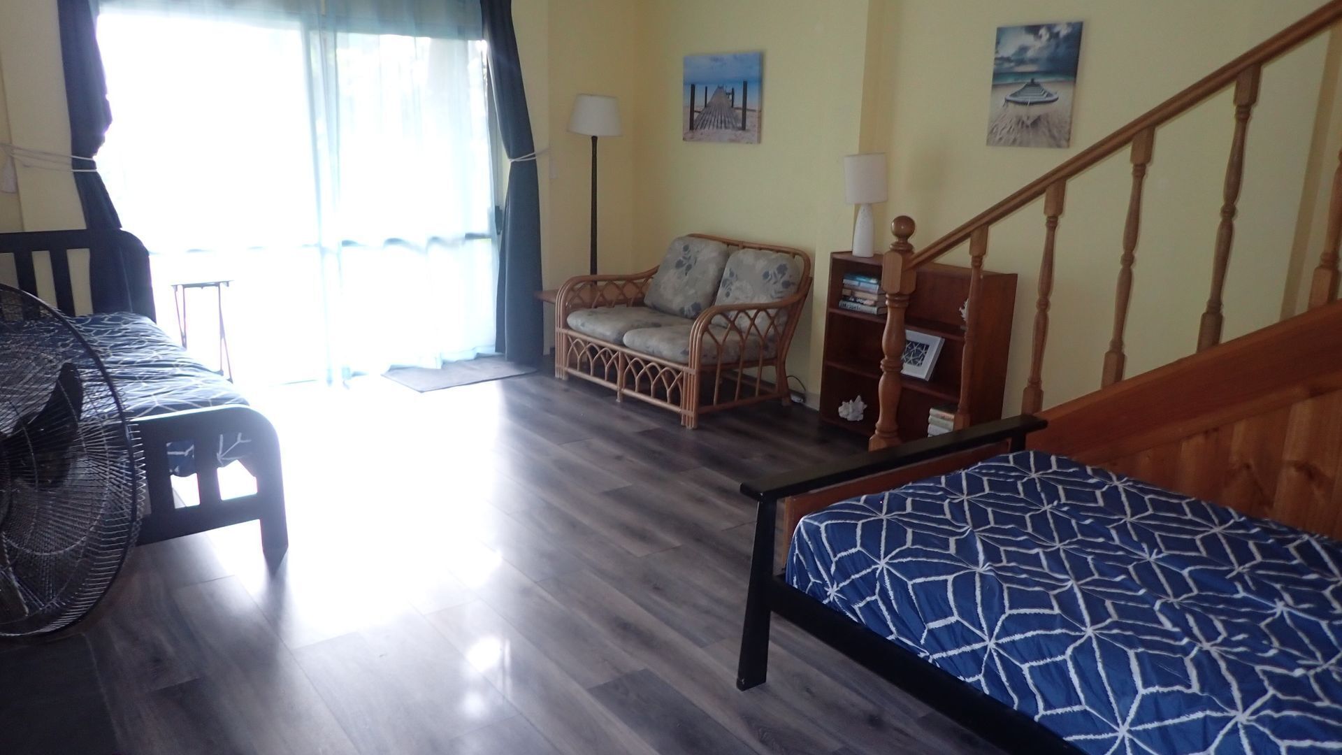 A room with a bed, a chair, a small table, and a staircase.