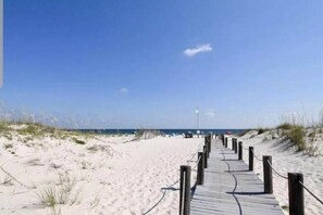 A wooden boardwalk leading to a beach with sand dunes and a clear blue sky. - Convenient 1st floor unit. Beautifully updated. Sleeps 6 (Gulf Shores)