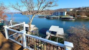 Una terraza con vistas a un lago, barcos amarrados y un edificio al otro lado del agua.