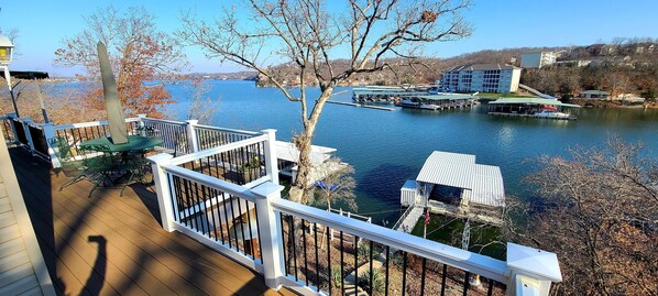 A deck with a view of a lake, docked boats, and a building across the water.