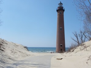 A tall brick lighthouse with a clear sky and ocean in the background.