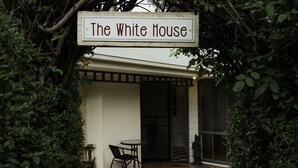 Ein überdachter Patio-Bereich mit einem Schild, das "The White House" zeigt, einem kleinen Tisch und einem Stuhl.
