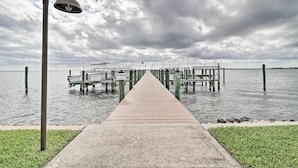 Un muelle de madera que lleva a un embarcadero con barcos y un letrero de 'Prohibido el paso'.