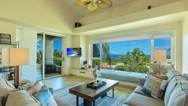 A modern living room with a large window offering a view of palm trees and the ocean. - Palms at Wailea  Spectacular Ocean Views with Exceptional Star Rating  (Kihei)