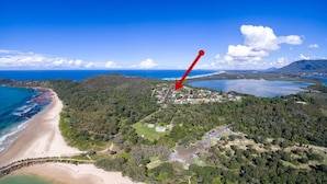 An aerial view of a coastal area with a beach, forested hills, and a small settlement. - Rio Grande - views of the bay and the beach (CAMDEN HEAD)
