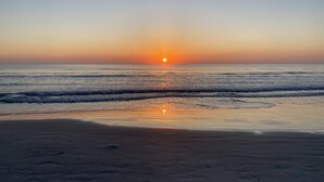 A beach with a sunset over the ocean. - Beach front condo with ocean views and community pool. 2/2 on non drive beach.  (New Smyrna Beach)